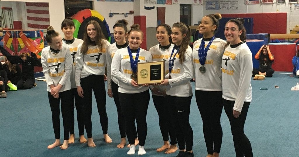 dynamic gymnastic gymnasts holding an award